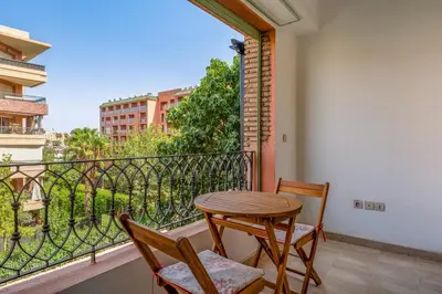 a balcony with a wooden table and two chairs at Cosy Palace elevator and pool in Marrakech