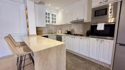 a kitchen with white cabinets and a granite counter top at L'Écrin by Louhou Collection - Plein centre in Marrakech