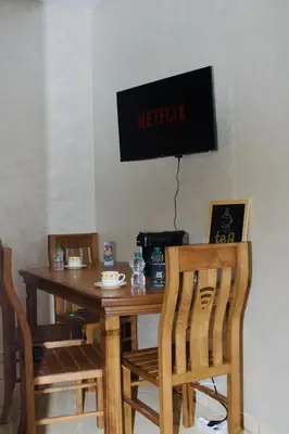 a wooden table with chairs and a television on the wall at Khamo Apartment, 15 min Walking to Airport, 15 min by Taxi to Medina in Marrakech