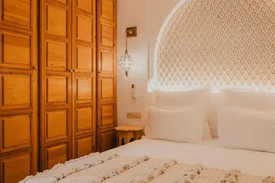 a bedroom with a white bed and wooden cabinets at Riad Al Mechouar in Marrakech