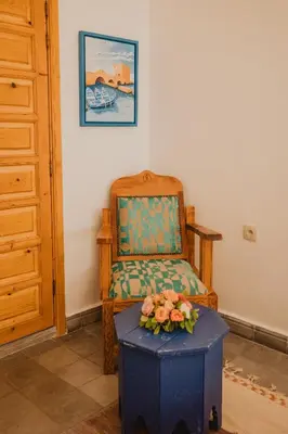 a room with a chair and a stool with flowers on it at Riad Al Mechouar in Marrakech