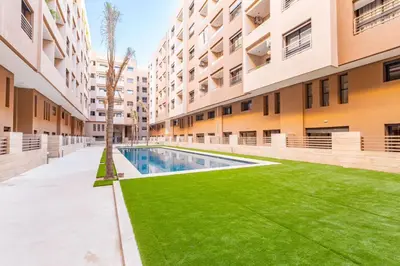 an apartment courtyard with a swimming pool and green grass at Appart 3 CH Menara Garden in Marrakech