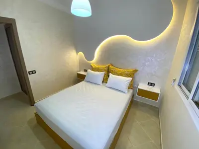 a small bedroom with a white bed with yellow pillows at Appartement à Marrakech confortable et équipe in Marrakech