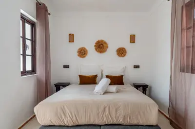 a bedroom with a white bed and two windows at Riad Zahra Private Pool and Breakfast10min Jemaa in Marrakech