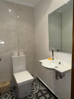 a white bathroom with a toilet and a sink at Bel Appartement 2 Chambres spacieux avec Piscine in Marrakech
