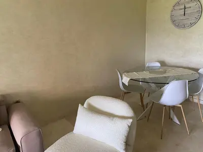 a dining room with a table and chairs and a clock at appartement à prestigia golf marrakech- SAPHIR in Marrakech