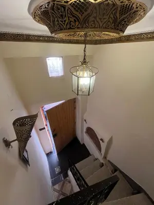 a chandelier hanging from a ceiling with stairs in a building at Riad Darkom Private in Marrakech