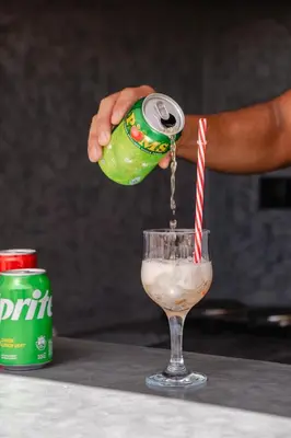 a person pouring a can of soda into a drink at Riad fabi in Marrakech