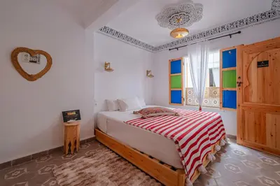 a bedroom with a bed with a red and white striped blanket at Riad fabi in Marrakech