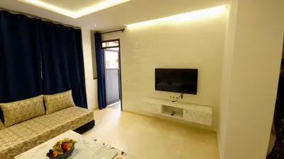 a living room with a couch and a tv on a wall at Charming Marrakech Appartement in Marrakech
