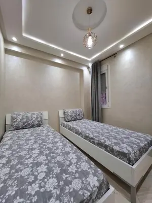 a bedroom with two beds and a chandelier at Modern Marrakech Apartment in Marrakech