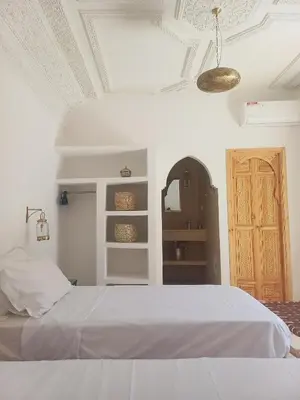 a bedroom with a white bed and a door at Riad DabaKech in Marrakech