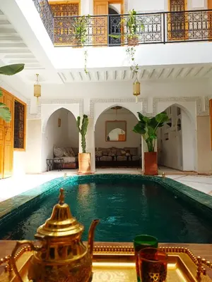 a large swimming pool in a large room with a house at Riad DabaKech in Marrakech