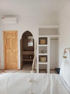 a bedroom with a white bed and a wooden door at Riad DabaKech in Marrakech