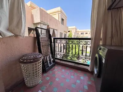 a balcony with a trash can next to a fence at L'escapade Marrakech - Appartement familiale vue sur Piscine in Marrakech