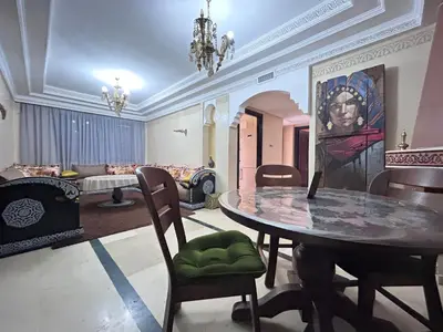 a dining room with a table and a painting on the wall at L'escapade Marrakech - Appartement familiale vue sur Piscine in Marrakech