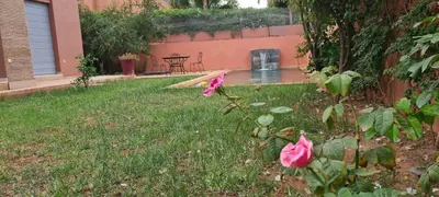 a garden with a table and pink roses in the yard at 5-star luxury villa with private pool in Marrakech
