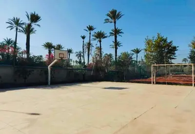 an empty basketball court with a goal and palm trees at Palmeraie village , lieu exceptionnel avec jardin et piscine in Marrakech