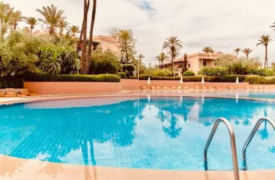 a swimming pool at a resort with palm trees at Palmeraie village , lieu exceptionnel avec jardin et piscine in Marrakech