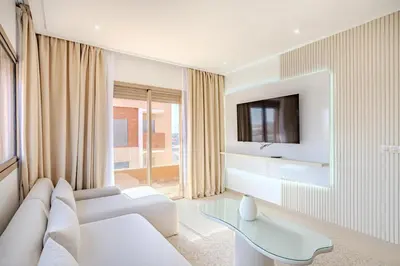 a living room with a white couch and a tv at Magnifique appartement moderne 1 chambre proche de la gare de Gueliz in Marrakech