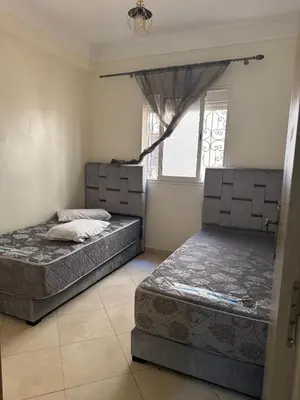 two beds sitting in a room with a window at 2BR w Balcony in Gueliz 2 Bedroom Apartment with Balcony in Gueliz in Marrakech