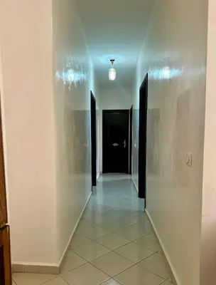 a hallway with black doors and a white wall at Appartement a louer in Marrakech