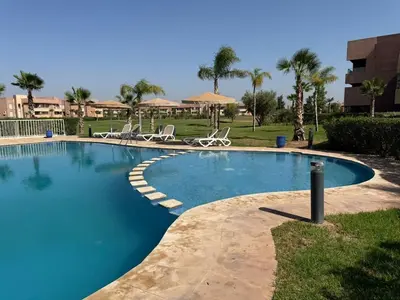 a large swimming pool with chairs in a resort at Elegant Apartment in Prestigia Pool & Golf in Marrakech