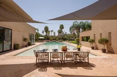 a dining table and chairs next to a swimming pool at Villa Sofya Domaine exceptionnel 10 suites & piscine privée in Marrakech