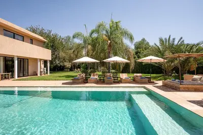 a swimming pool with chairs and umbrellas next to a house at Villa Sofya Domaine exceptionnel 10 suites & piscine privée in Marrakech