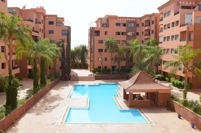 an empty swimming pool in a building with palm trees at Menara Palms Marrakech in Marrakech