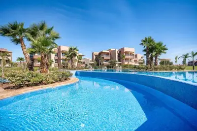 a large swimming pool with palm trees and buildings at Luxury Apartment - Prestigia Golf City Marrakech in Marrakech