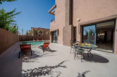 a patio with a table and chairs and a pool at Villa Assia Modern Luxury Private Pool in Marrakech