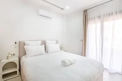 a white bedroom with a white bed and a window at Appartement 1 chambre proche de la gare de Gueliz in Marrakech