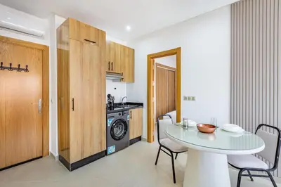 a room with a table and a kitchen with a washing machine at Appartement 1 chambre proche de la gare de Gueliz in Marrakech