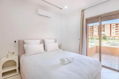 a bedroom with a white bed with a large window at Appartement 1 chambre proche de la gare de Gueliz in Marrakech