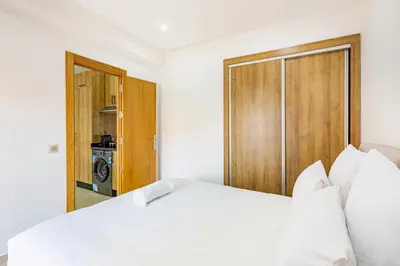 a bedroom with a white bed and a closet at Appartement 1 chambre proche de la gare de Gueliz in Marrakech
