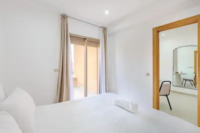 a white bedroom with a large bed and a mirror at Appartement 1 chambre proche de la gare de Gueliz in Marrakech