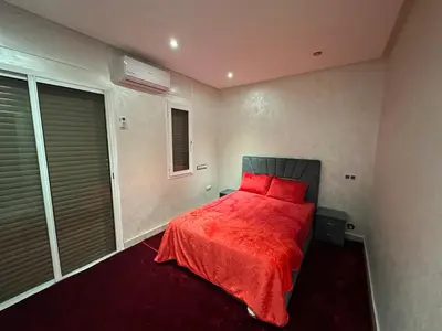 a bedroom with a bed with red sheets and a window at Achraf in Marrakech