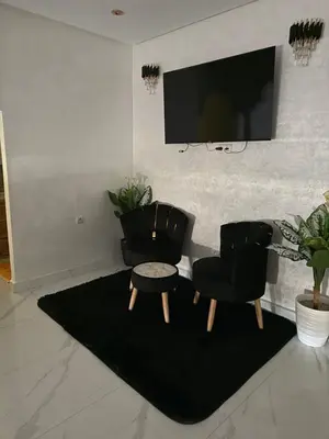 a living room with two chairs and a flat screen tv at Achraf in Marrakech