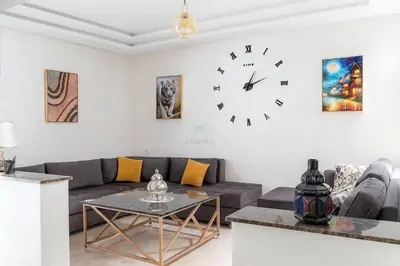a living room with a couch and a clock on the wall at Kridarek - Appartement d'exception à Marrakech in Marrakech
