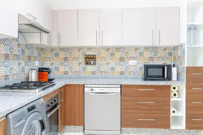 a kitchen with white cabinets and a washer and dryer at Kridarek - Appartement d'exception à Marrakech in Marrakech