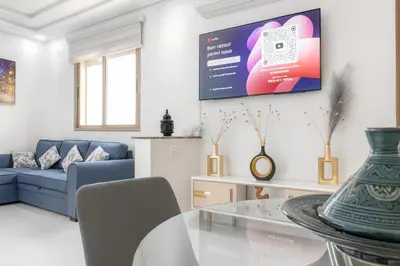 a living room with a table and a tv on the wall at Kridarek - Appartement d'exception à Marrakech in Marrakech
