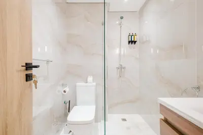 a bathroom with a toilet and a glass shower at NEW - Central 1BR-Kingsize, AC & Terrace Parking in Marrakech