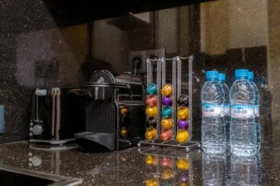 a counter with a coffee maker and bottles of water at NEW 1BR Apart Queensize AC 5 min to CityCenter in Marrakech