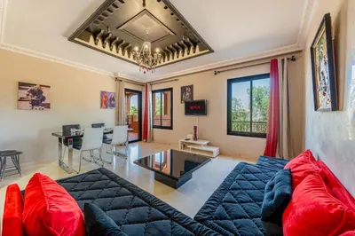 a living room with a blue couch and red pillows at Marrakech-Piscines-Salle Sport - 5 min du stade in Marrakech