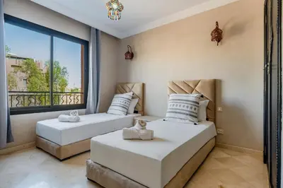 two beds in a room with a large window at Marrakech-Piscines-Salle Sport - 5 min du stade in Marrakech