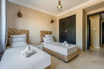 two beds in a room with white sheets and towels at Marrakech-Piscines-Salle Sport - 5 min du stade in Marrakech