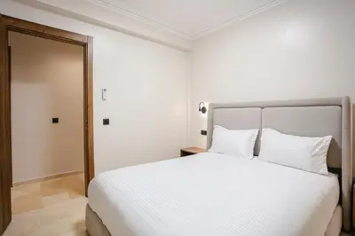 a bedroom with a white bed and a mirror at The Luxury Gate Duplex Private Pool in Marrakech