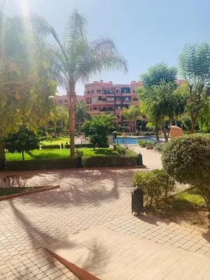 a park with palm trees and a building in the background at Modern apartment with pool & gym in Marrakech