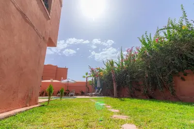 a garden with grass and bushes next to a building at Luxury private villa with heated pool in Marrakech